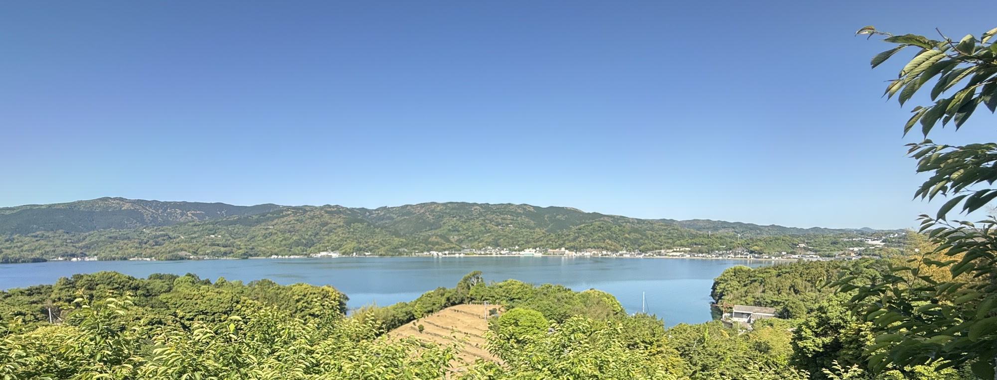 対岸の高台から見た形上。手前の緑のむこうに形上湾がひろがり、その先に家なみと連なる山